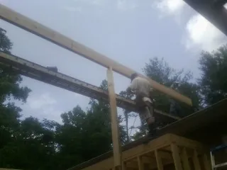 Carpenter setting a ridge beam over a new addition frame — Ice Dam Removal by Roofing Brothers in Sag Harbor
