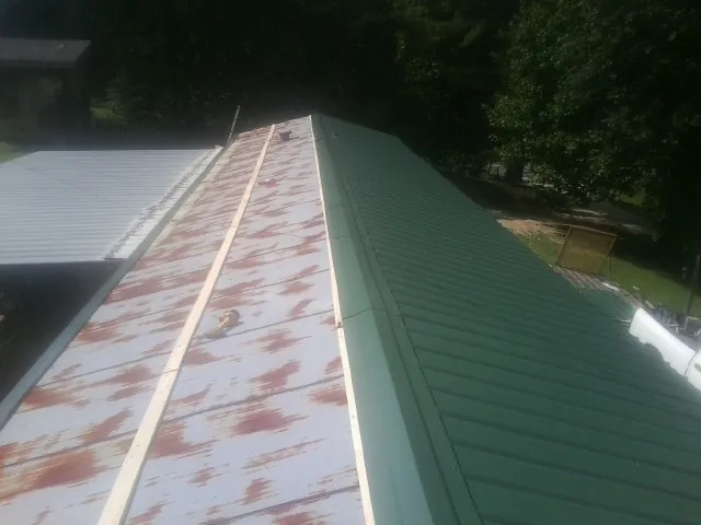 Old rusted panels beside newly installed green metal roofing — Wind Damage Roof Repair by Roofing Brothers in Sag Harbor