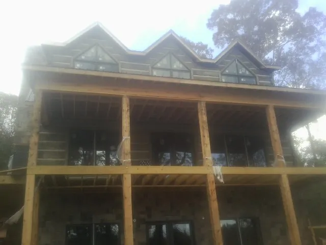 Dormers and porch framing on a large log home under construction — Roof Coating work by our crew in Sag Harbor
