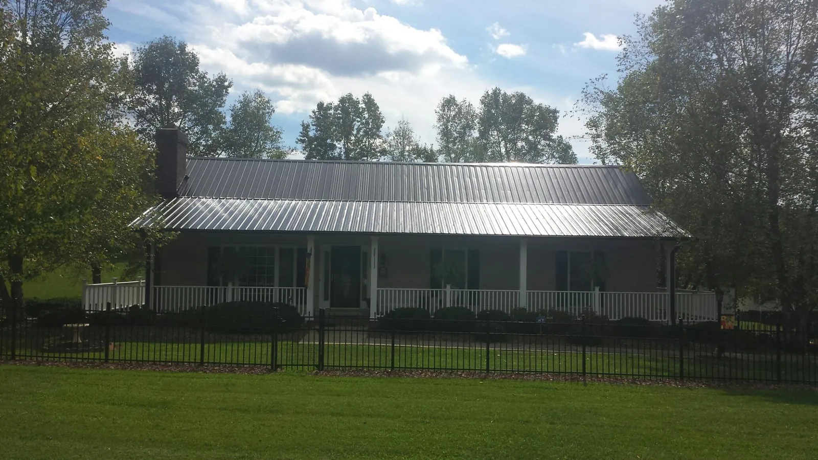 Gray metal roof on a brick ranch with a full width front porch — Gutter Guard Installation work by our crew in Sag Harbor