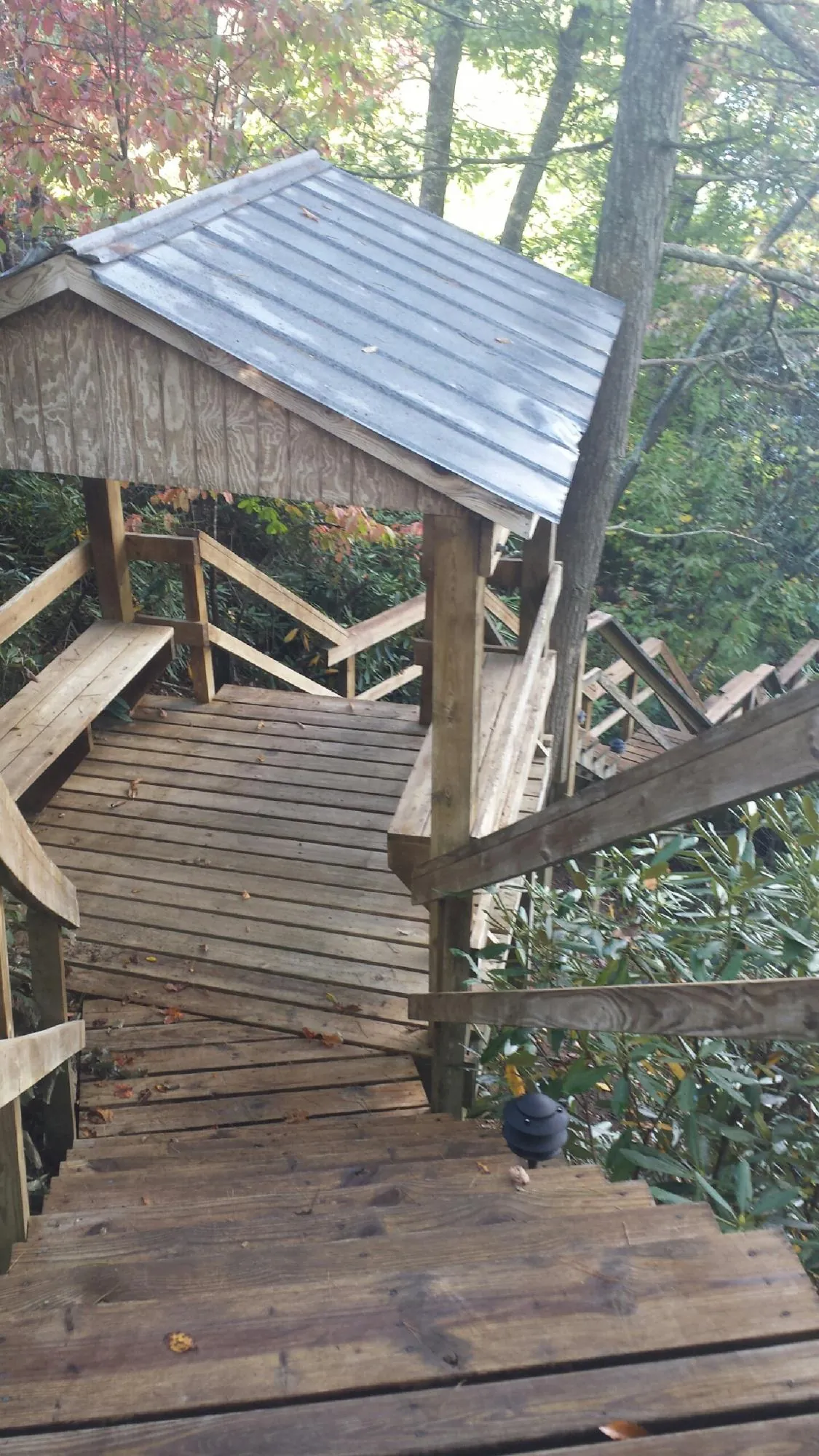 Metal roofed shelter over wooden steps on a wooded walkway — Skylight Repair & Installation work by our crew in Sag Harbor