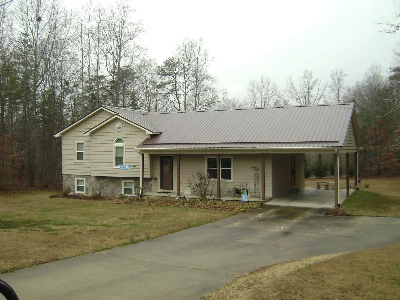 Brown metal roof on a tan split level home with an attached carport in Sag Harbor