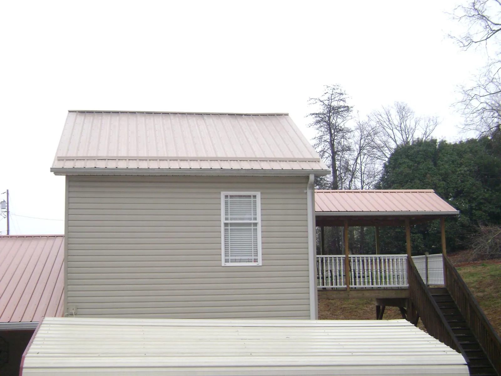 Tan metal roofs on a two story addition and attached porch, from a Roof Replacement job in Sag Harbor
