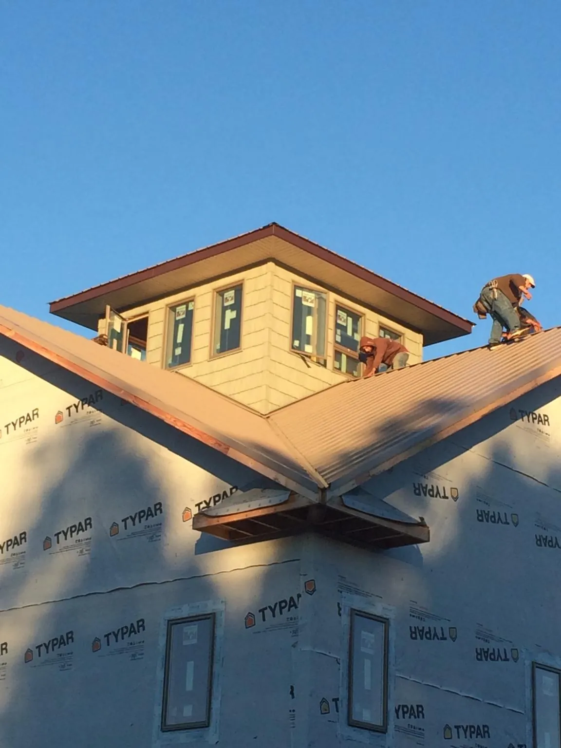 Roofers working around a rooftop cupola on a new metal roof at sunset — Roof Waterproofing in Sag Harbor by Roofing Brothers
